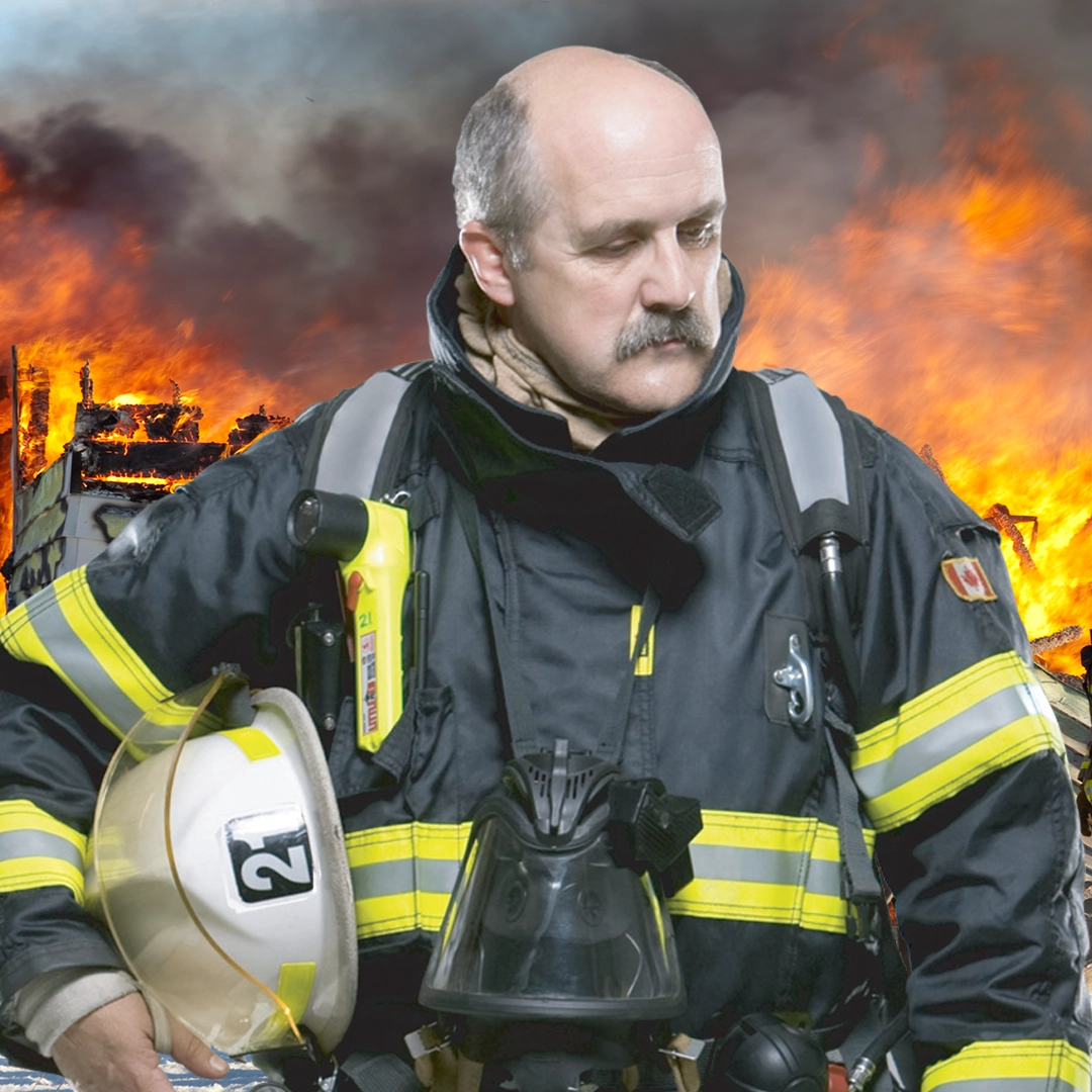Firefighter in gear holding helmet before burning building