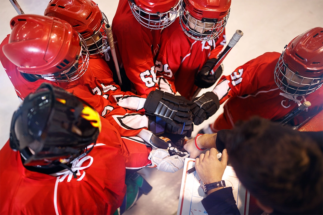 Youth hockey team huddling with coach on ice